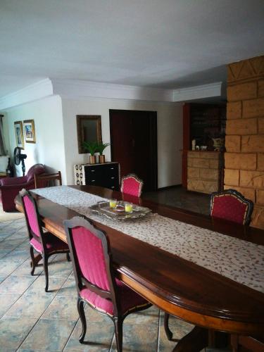 una sala da pranzo con un grande tavolo in legno e sedie rosa di Condor House a Centurion