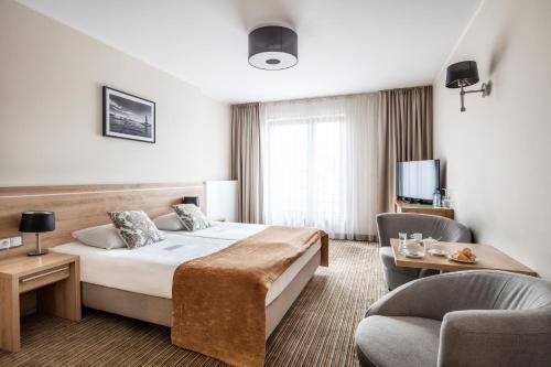 pokój hotelowy z łóżkiem i 2 krzesłami w obiekcie Mercure Wiazowna Brant w mieście Wiązowna