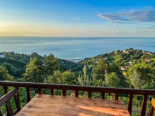 a wooden table on a balcony overlooking the ocean at Kaf Dagi Konak Hotel in Rize
