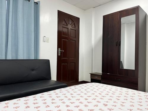 a bedroom with a bed and a cabinet and a mirror at HRS APARTELLE in Talisay
