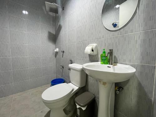 ein Badezimmer mit einem WC, einem Waschbecken und einem Spiegel in der Unterkunft HRS APARTELLE in Talisay
