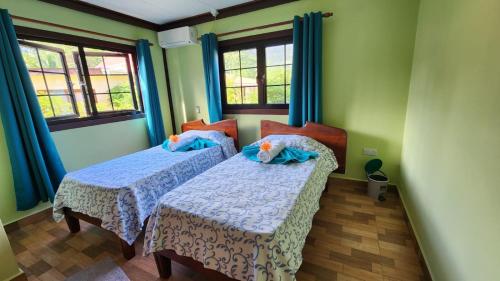 2 łóżka w pokoju z zielonymi ścianami i oknami w obiekcie Lianita's Cottage (Selfcatering) w mieście La Digue