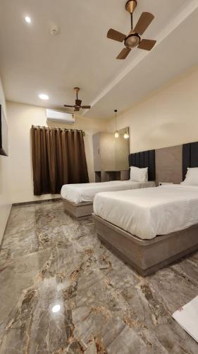 a bedroom with two beds and a ceiling fan at Peace International in Mumbai