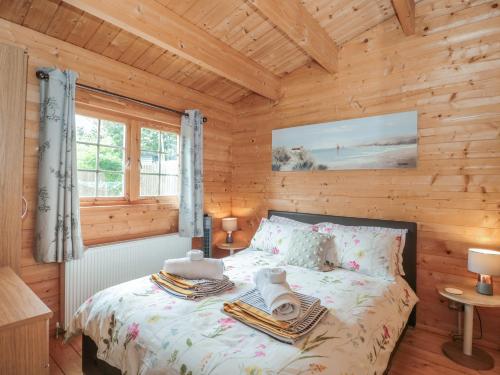 een slaapkamer met een bed in een blokhut bij Pigsfoot Lodge in Tiverton