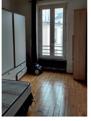 a room with a bed and two windows and a wooden floor at A 10 minutes à pied du stade de France , 35 m2 très cosy refait à neuf in Saint-Denis