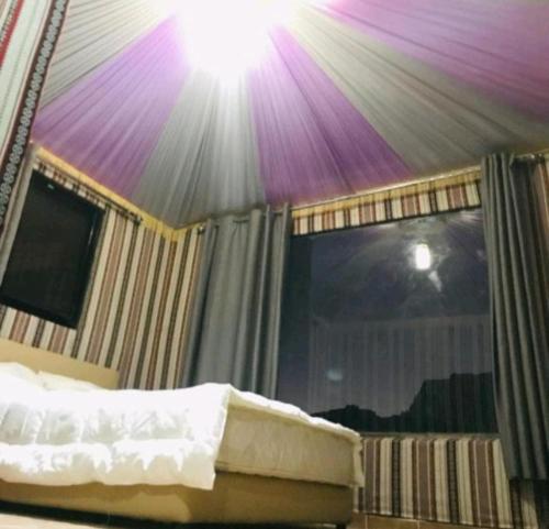 a bedroom with a bed with a purple ceiling at Wadi Rum Aviva camp in Wadi Rum