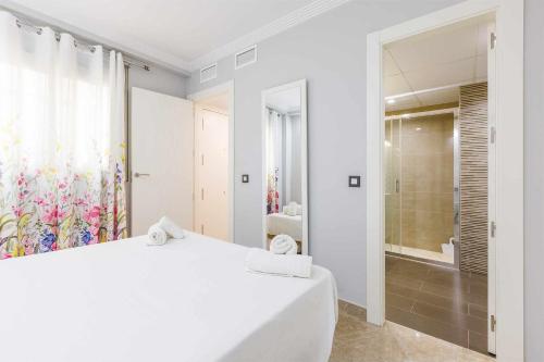 a white bedroom with a large white bed and a shower at A&N La Cueva 2 in Torre del Mar