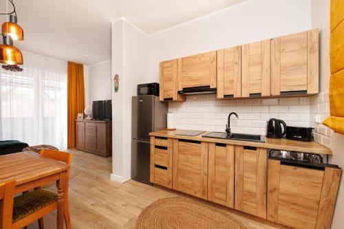 a kitchen with wooden cabinets and a table with a dining room at Apartament Toskański in Rewal