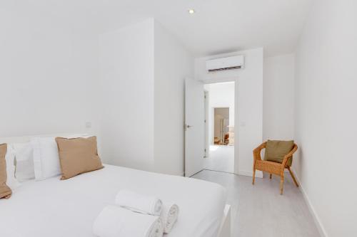um quarto branco com uma cama e uma cadeira em Alcantara Charm 3BR Apartments em Lisboa