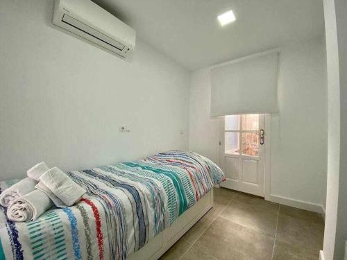 a white bedroom with a bed with towels and a window at A&N DownTown in Torre del Mar