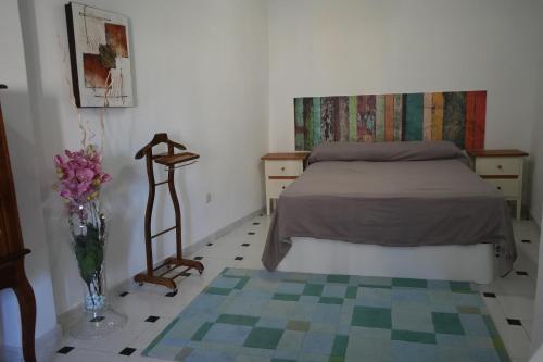 1 dormitorio con 1 cama y un jarrón de flores en Casa Margarita en Peñaranda de Duero