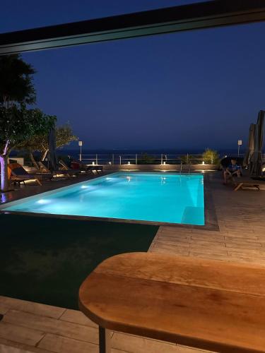 a swimming pool at night with a wooden table at Luxury Villa Magic View 4U - katarina in Kineta