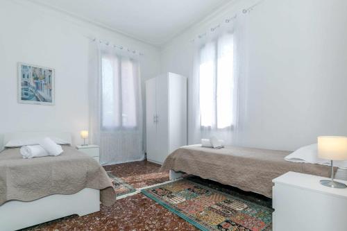 a white bedroom with two beds and windows at 11 Venice Garden Private garden parking free in Marghera