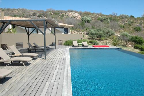 a swimming pool with chairs and a wooden deck at Chambres d'Hôtes Bianca Casa in Porto-Vecchio