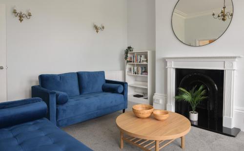 a living room with a blue couch and a table at Flat 2, 10 Seafield Road in Seaton