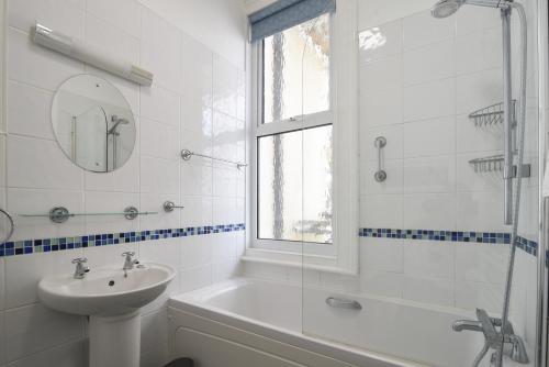 ein weißes Bad mit einem Waschbecken und einer Dusche in der Unterkunft Flat 2, 10 Seafield Road in Seaton