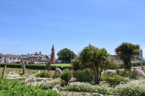 a garden with palm trees and a clock tower in the background at Flat 2, 10 Seafield Road in Seaton