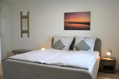 Un dormitorio con una cama blanca con dos luces. en Pier 35, en Kirchdorf