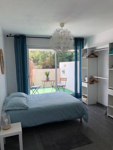 une chambre avec un lit et une grande fenêtre dans l'établissement Agréable T2 traversant RDC avec terrasse - balcon - Parking 2 places - Clim portative, à Montpellier