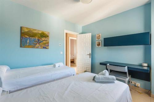 een blauwe kamer met 2 bedden en een bureau bij A&N Luxury Seaside Traiñas in Caleta De Velez