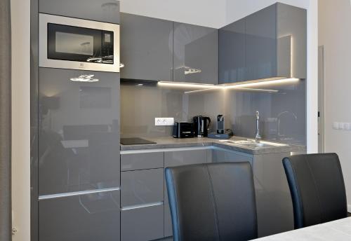 a kitchen with gray cabinets and a microwave and chairs at Aquamaris Strandresidenz Rügen in Juliusruh
