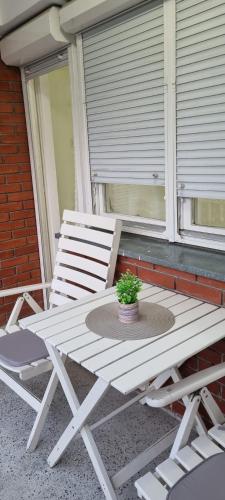 un banco blanco sentado en un porche con una planta en Apartmani Cvetković, en Vrnjačka Banja