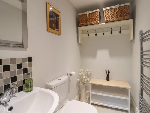 a bathroom with a white toilet and a sink at Spindlewood Cottage in Cranbrook