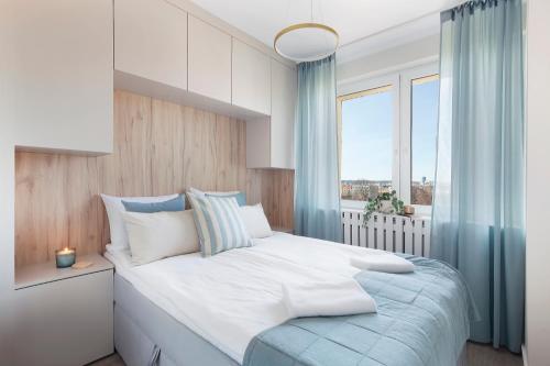 a bedroom with a large bed and a window at Elite Apartments Sandy in Gdańsk