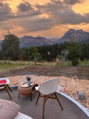 a patio with two chairs and a table and mountains at Bubble Tent Füssen im Allgäu in Füssen