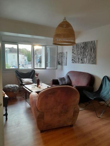 a living room with a couch and a table and chairs at Charmant logement avec parking gratuit sur place in Éclaron