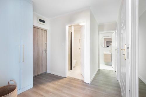 a white hallway with white walls and wood floors at Elite Apartments Sandy in Gdańsk
