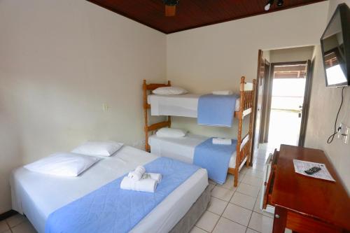 a bedroom with two beds and a desk and a desk at Pousada Albamar Guarujá in Guarujá