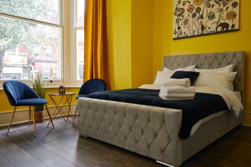 a bedroom with a large bed with blue chairs and a window at LUXURY Holiday Home Elizabeth Line in London