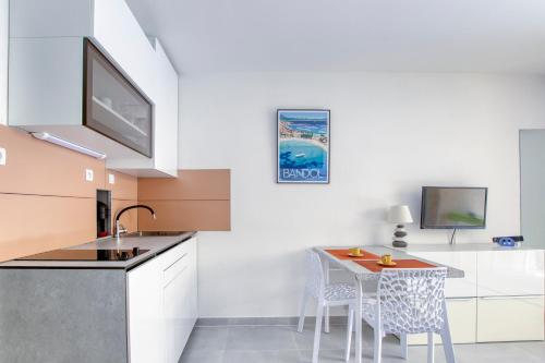 une cuisine avec un évier et une table avec des chaises dans l'établissement Isulita - Studio climatisé à 400m de la mer, à Bandol