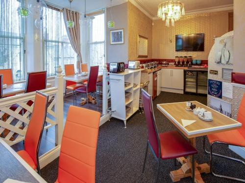a restaurant with orange chairs and a table and a kitchen at The Llandudno Hotel in Llandudno