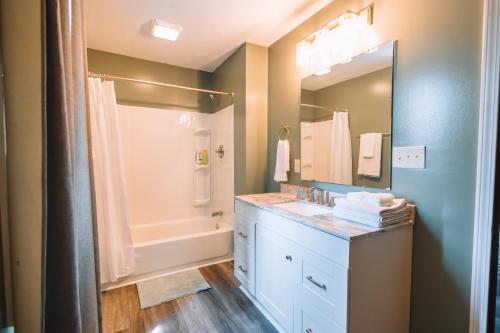 a bathroom with a sink and a shower and a mirror at Downtown Escape Great for large families & groups in Sugarcreek