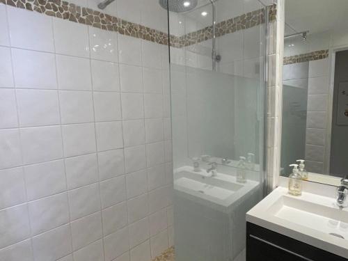 a white tiled bathroom with a sink and a shower at Appartement Saint-Raphaël, 1 pièce, 4 personnes - FR-1-504-567 in Saint-Raphaël