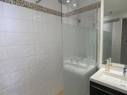 La salle de bains est pourvue de carrelage blanc, d'un lavabo et d'une douche. dans l'établissement 2 pièces en rez-de-jardin avec vue mer, piscine et parking à Saint-Raphaël - FR-1-504-567, à Saint-Raphaël