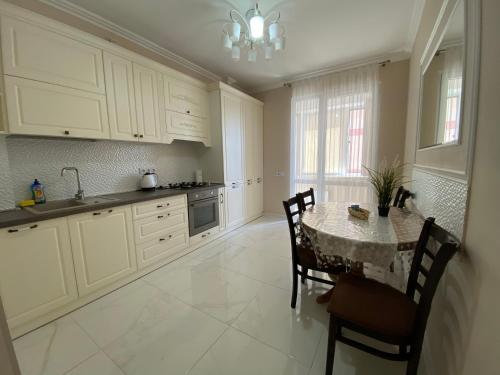 a kitchen with a table and chairs and a kitchen with white cabinets at Apartament lux in Chişinău