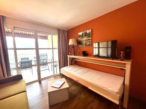een slaapkamer met een bed, een televisie en een balkon bij Appartement Saint-Raphaël, 3 pièces, 6 personnes - FR-1-504-418 in Saint-Raphaël