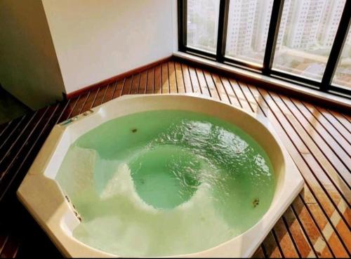 a bath tub filled with green water next to a window at Golden Flat's - Slaviero Guarulhos in Guarulhos