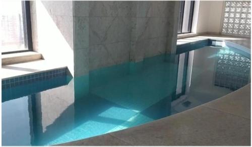 a swimming pool with blue water in a building at Golden Flat's - Slaviero Guarulhos in Guarulhos