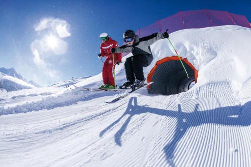 two people on skis on a snow covered slope at La Tgoma - Hotel & Restaurant in Lenz