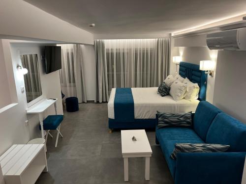 a hotel room with a bed and a blue couch at Ocean Blue Suites in Ierissos