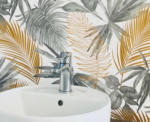 a bathroom sink with a faucet and a mural of leaves at Canaryislandshost l Sal de Mar in Puerto del Carmen