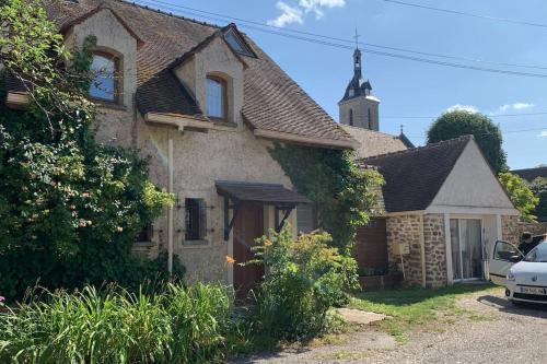 una casa vieja con una iglesia en el fondo en La Cour Des Jardins en Neufmoutiers-en-Brie