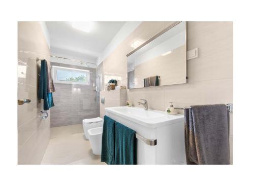 Un baño con lavabo, inodoro y espejo. en Villa Ventitre, Privatpool,Meersicht, nahe Porec- Strand NEU, en Mugeba