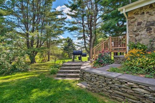 a backyard with a stone wall and a wooden deck at Catskills Farmhouse and Spa in Harpersfield