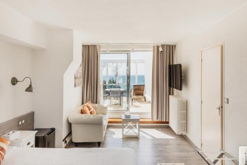 een slaapkamer met een bed en een stoel en een balkon bij Hôtel Édenia - Spa Estime&Sens in Carnac