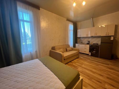 a bedroom with a bed and a couch and a kitchen at Apartments NITA in Batumi